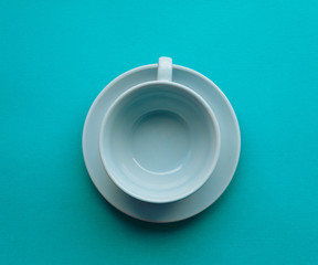 Empty blue tea cup and saucer on a turquoise background top view.