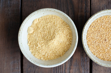 Canadian flax-seeds in bowl and ground linseed on wooden background. Top view