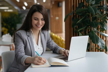 Portrait of smiling successful businesswoman working in modern office. Beautiful woman freelancer...