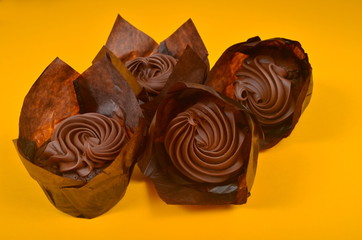 Four Muffin with chocolate cream on a yellow background, surrounded by coffee beans