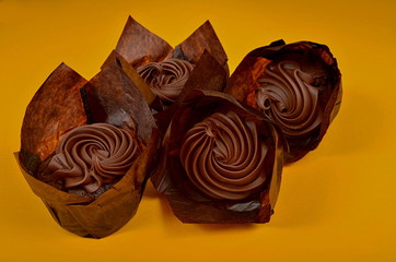 Four Muffin with chocolate cream on a yellow background, surrounded by coffee beans