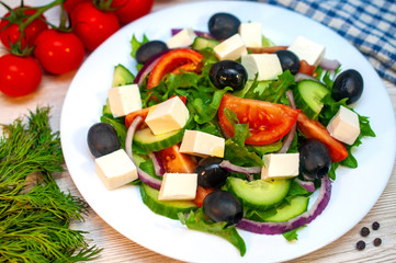 Greek salad with tomatoes, cucumbers and feta cheese with olives on the table