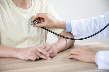 Doctor or nurse advice  to man patient in hospital  while examining the patients pulse, heart rate by stethoscope and hands. Healthcare and medical service. (select focus)