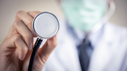 Doctor or nurse hand holding stethoscope in hospital with copy space