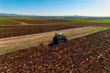 aerial view of the tractor plows in the field,