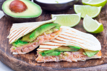 Grilled quesadilla with smoked salmon and avocado served with yogurt and lime dip, on  wooden board, horizontal, closeup