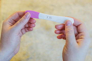 Woman holding positive pregnancy test.