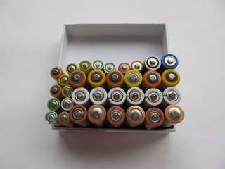 Used batteries in a white box are ready for the disposal, on a light background. Ecology concept.