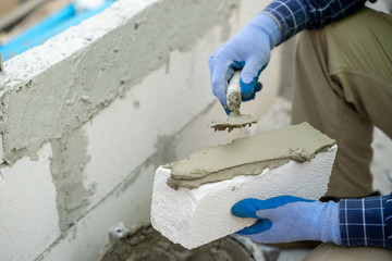 Plastering the wall.Hand holding a spatula with construction mix.Applying putty or tile glue to...