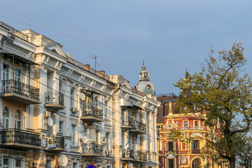 Obraz premium Rząd starych budynków uchwyconych podczas złotej godziny w Kijowie na Ukrainie. Budynki mają różne kolory, ze szczegółową i ozdobną fasadą. Wielkomiejskie życie.