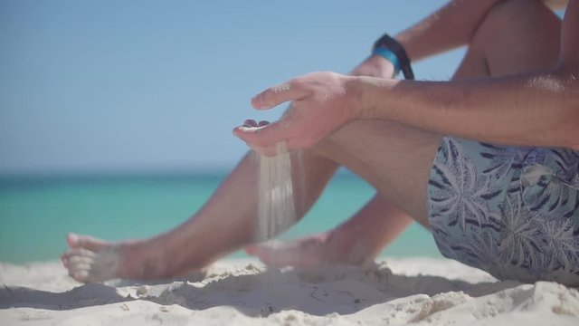 Guy Relaxing On Tropical Beach.Happy Calm Healthy Young Man Resting On Ocean.Hand Playing With Sand On Bahamas Vacation Holiday.Man Pouring Sand Through Fingers.Guy Sitting On Beach Caribbean Coast 