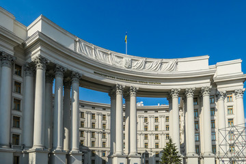 Obraz premium A building of Ministry of foreign Affairs of Ukraine. Marble white arch, with Ukrainian flag on top of it. Arch is supported on thin pillars. Clear and blue sky above the construction