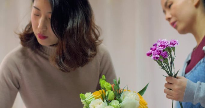 4k,chinese young girl florist is training her pregnant friend flower arrangement skills, she showing her collocation and adjustment of bouquets,in chengdu china