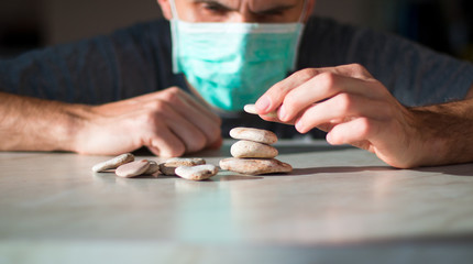 man in medical mask is building pyramid of stones and waiting for healing
