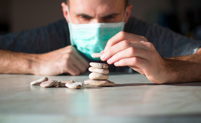 man in medical mask is building pyramid of stones and waiting for healing
