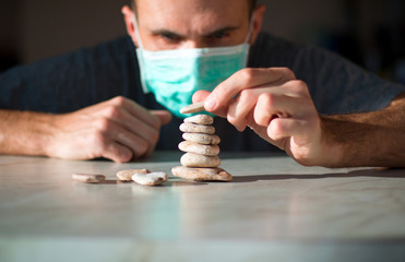man in medical mask is building pyramid of stones and waiting for healing