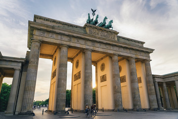 Obraz premium Two cyclists in Brandenburg gate at sunset, Berlin, Germany