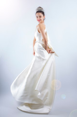 Fototapeta premium Portrait of a beautiful girl in a wedding dress. Dancing Bride, gray background. Isolated