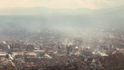 Soft, hazy view of smog over city, polluted by smoke coming from chimneys of the houses using wood for heating