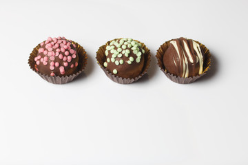 Chocolate Potato Cake. Some decorated with sprinkles, others with chocolate. On white background.