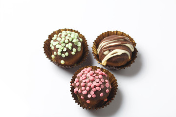 Chocolate Potato Cake. Some decorated with sprinkles, others with chocolate. On white background.