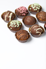 Chocolate Potato Cake. Some decorated with sprinkles, others with chocolate. On white background.