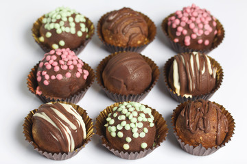 Chocolate Potato Cake. Some decorated with sprinkles, others with chocolate. On white background.
