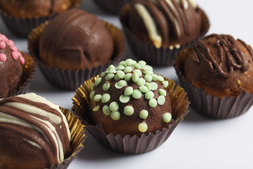 Chocolate Potato Cake. Some decorated with sprinkles, others with chocolate. On white background.