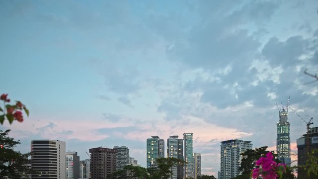 Modern city landscape. Timelapse of sunset. Modern skyscrapers made of glass and concrete. Green city with trees.