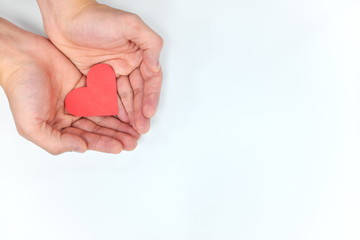 Fototapeta premium Open hands holding red heart. Top view, white background. Life insurance, healthy heart, and healthcare concept.
