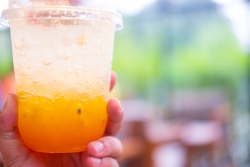 Hand holding a glass of fresh passion fruit juice mix with soda