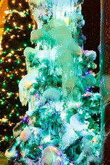 Christmas tree frozen in ice, close-up, luminous decorations.