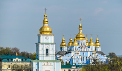Fototapeta na wymiar St Michael's Golden-Domed Cathedral in Kiev, Ukraine. The walls of the cathedral are painted blue and nicely decorated on each facade. Golden domes are reflecting the strong sun.