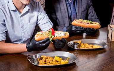 Two hungry young men eating a hot dogs in cafe. Restaurant