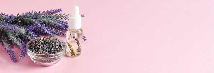 Bunch of lavender flowers, dried lavender and aromatic lavender oil on pink background.