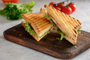 Cheese sandwich of toasted bread with a crispy crust with fresh tomatoes and herbs on a wooden board