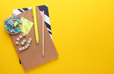 Flat lay composition of notebooks, pencil,pen,binders.Copy space,yellow background.Top view on...