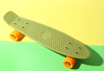 Green skateboard with orange wheels on yellow and green background. Plastic mini cruiser board....