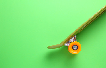 Close up of green skateboard with orange wheels on green background. Plastic mini cruiser board. Creative concept. Minimalism, flat lay, copy space © CamelCase