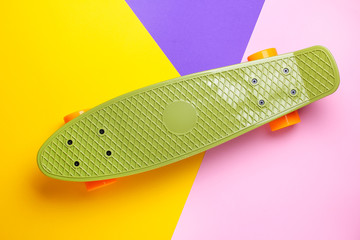 Green skateboard with orange wheels on yellow,purple and pink background. Plastic mini cruiser...