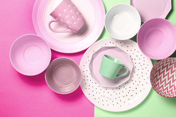 Empty ceramic tableware. Ceramic plates and cups on pink and green background. Set of different modern white and blue plates,bowls and cups.Top view, flat lay.Copy space.