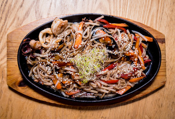 Chinese noodles with mussels and shrimps on the wooden table.