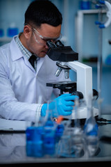 Young scientist looking through a microscope in a laboratory. Young scientist doing some research.