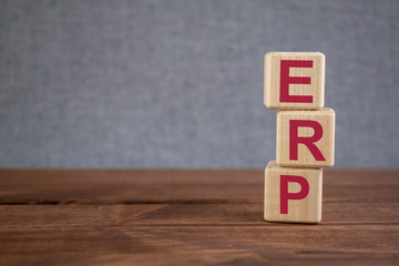 ERP (Enterprise Resource Planning) acronym on wooden cubes on dark wooden backround. Business...