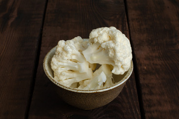 Fototapeta na wymiar cauliflower in clay bowl on wooden background