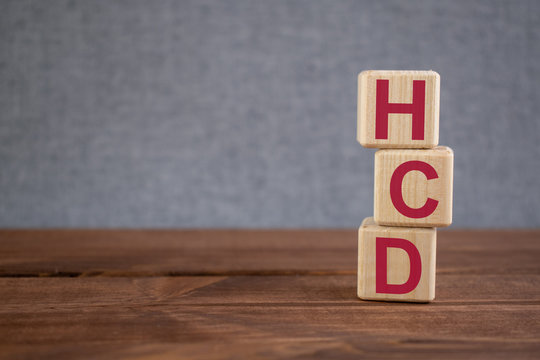 HCD (Human Capital Development) acronym on wooden cubes on dark wooden backround. Business concept.