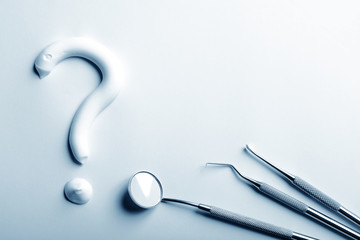 Dental instruments and a tooth paste question mark in blue monochrome. Dental treatment concept.
