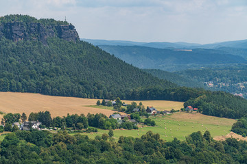 Fototapeta na wymiar Königstein fortress on the banks of the Elbe river, green landscape with mountains in the background. Dresden, Saxon Switzerland, Germany.