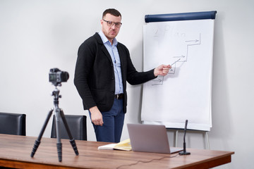Young video blogger presenting important data on flipchart, online education concept