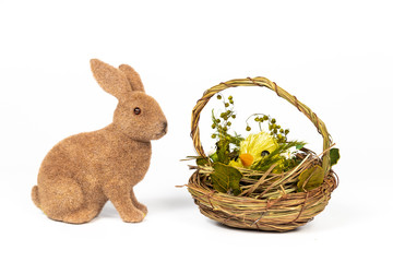 Easter rabbit looking on chicken inside straw Easter basket isolated on white background. Studio shoot